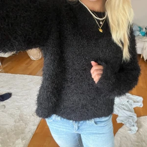 Svart fluffig stickad tröja - Mysig svart stickad tröja med fluffig textur och lång ärm. Tröjan har en rak passform och är perfekt för kyligare dagar. Enkel att matcha med jeans eller kjol för en avslappnad look. Kolla min sida för fler snygga plagg