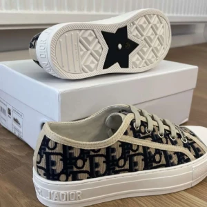Dior sneakers  - Snygga Dior Granville sneakers i blått och beige med broderat monogrammönster. Skorna har vit platt sula med Dior-logga, snörning och rund tå. Tillverkade i canvas med exklusiv känsla och cool design. Perfekta för dig som vill sticka ut med lyxiga detaljer.