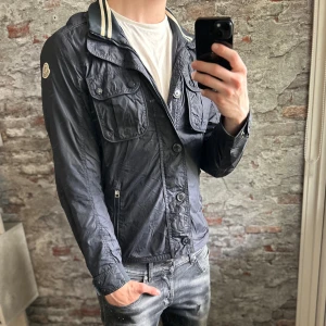 Moncler Field Jacket - Acceptabelt skick, jackan är urtvättad och lite smtusig. Storlek 2/M passar dig som är mellan 178-188. Nypris ca 8000kr. Självklart äkta, certiligo kod finns samt att jackan såldes från Holméns Herrekipage. Modellen är 185 cm, 79 kg. Passar bra till regninga och blåsiga dagar. Skriv för mer information!🤝