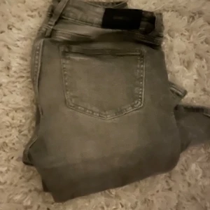 Grå jeans från Gina Tricot, storlek 158 - Snygga grå jeans från Gina Tricot i storlek 158. Klassisk femficksmodell med raka ben och normal passform. Jeansen är tillverkade i bomullsmix och har en stilren look som passar till det mesta. Perfekta för dig som gillar enkel och clean stil.