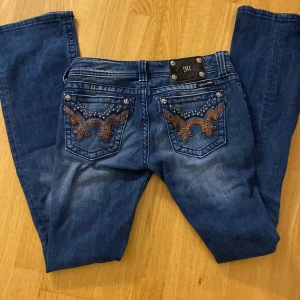 Blå Miss Me bootcut jeans med brodyr - Blå miss me jeans köpta på Vinted men andvänder inte dom ! Jag har andvänd typ 2 gånger. Ytterbenslängd 105 cm innerbenslängd 85 cm. Jag är 175 och dom är lite långa på mig! Skriv om du har några funderingar.