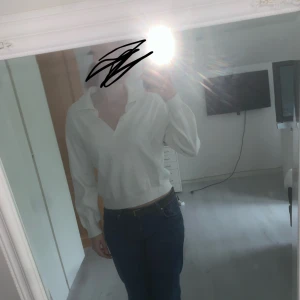 Vit v-ringad tröja - Säljer en vit tröja från Amisu med v-ringad hals och krage. Tröjan har långärmade ärmar och är i mjukt material. Passformen är normal och den är enkel att matcha med jeans eller kjol. Perfekt för dig som gillar clean och stilren look.