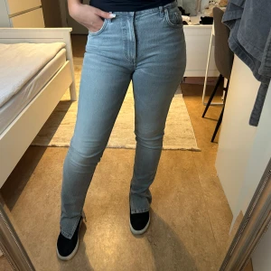 Gråa straight jeans med slits - Säljer ett par ljusgråa jeans med hög midja, och slits från Zara. Storlek 36! Använd ett fåtal gånger.