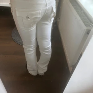 Vita jeans med fickor - Snygga vita jeans med slim passform och raka ben. Byxorna har klassiska fickor fram och bak, varav bakfickorna har lock och knapp. Perfekta för dig som vill ha en fräsch och stilren look. Stängs med knapp och dragkedja. Skulle säga att dom är mid waist grenen är 19cm. En gammal modell från Gin,w28
