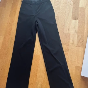 Svarta kostymbyxor från Vero Moda XS - Svarta kostymbyxor från Vero Moda i storlek XS/30. Byxorna har raka ben, normal passform och klassisk design med hällor för bälte och sidfickor. Perfekta för en clean och stilren look.