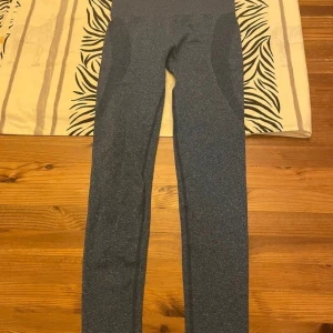 Mörkgrå leggings i stretchig nylon - Snygga mörkgrå leggings i mjukt och stretchigt material, perfekta för träning eller chill. Hög midja och figurnära passform som sitter skönt hela dagen. Tillverkade i 90% nylon och 10% spandex för maximal komfort och rörelsefrihet.