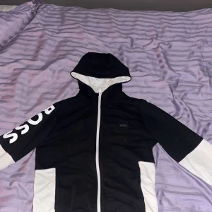 Svart och vit hoodie från BOSS - Hjälper en vän sälja en Hugo boss tröja, storleken är 14-s och skicket är 9/10 har använts men inte nån defekt. Mitt pris 350 nytt pris är runt 1100, kontakta oss gärna om ni har några funderingar så löser vi de!