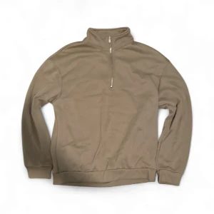 Beige half zip sweatshirt - Beige sweatshirt med half zip och hög krage. Tröjan har lång ärm, ribbade muddar och är tillverkad i mjukt material som känns skönt mot huden. Perfekt för lager-på-lager och chill dagar.