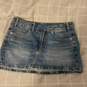 Jeanskjol - Snygg blå jeanskjol i klassisk modell med fem fickor, bälteshällor och dragkedja framtill.  