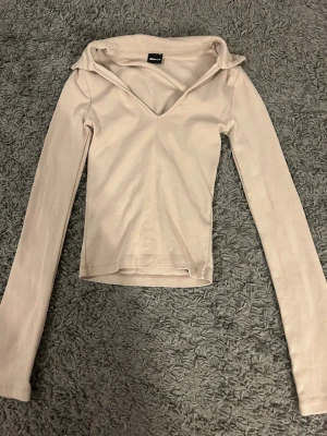 Beige långärmad topp Gina Tricot - Säljer en beige långärmad topp från Gina Tricot. Toppen har v-ringad halsringning och är tillverkad i ett mjukt, stretchigt material som sitter snyggt på kroppen. Perfekt att matcha med jeans eller kjol för en clean look.