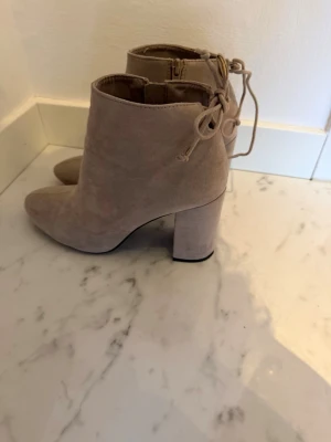 Beige stövletter med knytning bak - Går att knyta en rosett där bak. Används 3 gånger, köptes från pull and bear. Storlek 36