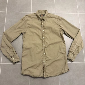 Grön skjorta från Morris - Stilren grön skjorta från Morris med klassisk krage och knäppning framtill. Skjortan har långa ärmar och en liten broderad logga på bröstet. Perfekt för en avslappnad men ändå uppklädd look.