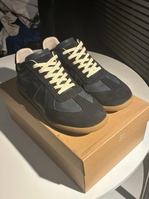 Riktiga Maison Margiela skor  - Snygga mörkblå sneakers med kontrasterande vit snörning och gummisula. Riktiga Maison margiela skor köpta på farfetch, använda kanske 10 ggr inge defekter. Digitalt kvitto skickas om man frågar, kvittot på bilden är order kvitto som man får med när paketet anländer, vilket innerhåller min information vilket inte kommer följa med vid köp samt dustbagen och boxen.                                                            🤝pris går att diskutera vid snabbt köp🤝