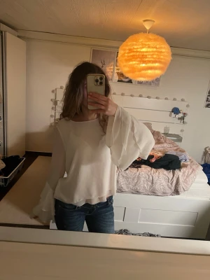 Vit blus med vida ärmar - Säljer en vit blus med transparent, flowy material och riktigt vida, långa ärmar i flera lager. Blusen har en lös passform och rund halsringning. Perfekt för dig som gillar en bohemisk och trendig stil.