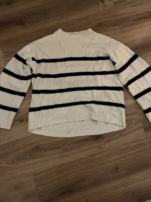 Vit och svart randig stickad tröja - Säljer en vit stickad tröja med svarta ränder. Tröjan är ribbad. 