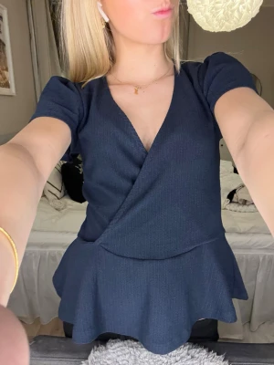 Mörkblå omlottopp - Supersnygg mörkblå omlottopp från Holly & White (Lindex) med v-ringning, korta puffärmar och volangkant nedtill. Knappt använd.❣️❣️