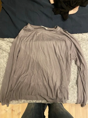 Ljuslila stickad tröja från Zara - Säljer en tunn, ljuslila stickad tröja från Zara. Tröjan har rund halsringning, långa ärmar och ribbade muddar vid ärmslut och nederkant. Perfekt för lager-på-lager och enkel att matcha med olika outfits.