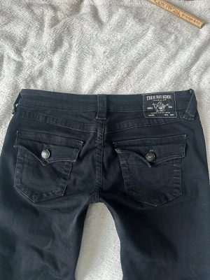 Svarta lågmidjade True Religion - Passar bra på mig som har storlek M. Innerbensländen är 84cm, midjemåttet är 40cm och grenhöjden är 19cm. Jeansen är lite slitna längst ner, skriv för fler bilder💕