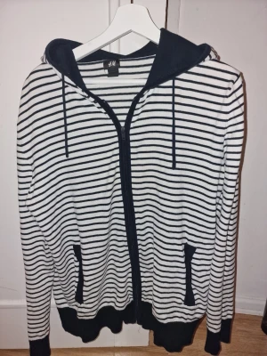 Randig hoodie i marinblått och vitt - Snygg hoodie i marinblått och vitt. Perfekt för en avslappnad och trendig stil. Tillverkad i mjukt material för extra komfort.