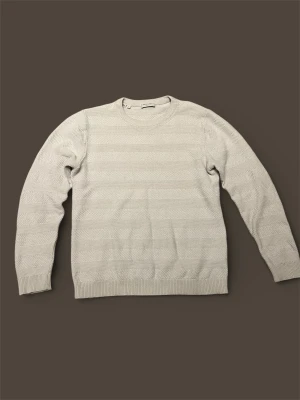 Beige stickad tröja från SELECTED HOMME - Snygg beige stickad tröja med diskret strukturmönster och rund hals. Tröjan har långa ärmar och ribbade muddar vid ärmslut och nederkant. Perfekt för dig som gillar en clean och stilren look.