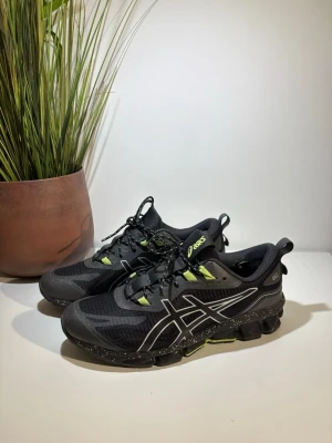 Svarta Asics sneakers med neongröna detaljer - Snygga svarta Asics sneakers med neongröna detaljer och reflekterande logga på sidan. Skorna har en chunky sula med GEL-dämpning och meshmaterial för bra ventilation. Perfekta för dig som gillar sportig stil och vill sticka ut lite extra.