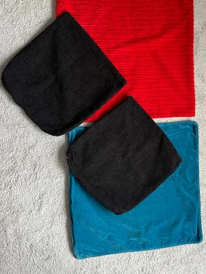 Fyra kuddfodral  - Säljer två stora kuddfodral, ett i röd manchester och ett i blå sammet. Båda är fyrkantiga och har dragkedja. Samt två mindre grå i ”sofftygsmatetial” även där dragkedja. Fyra för 50kr