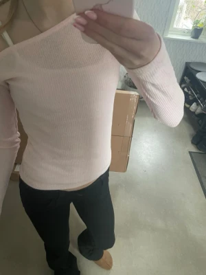 Ljusrosa ribbad offshoulder topp - Supersöt ljusrosa ribbad topp med offshoulder-design och långa ärmar. Perfekt att styla med jeans eller kjol för en trendig look.