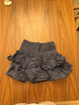 Mörkblå volangkjol med broderi - Supersöt mörkblå kortkjol med bred resår i midjan och flera lager volanger. 