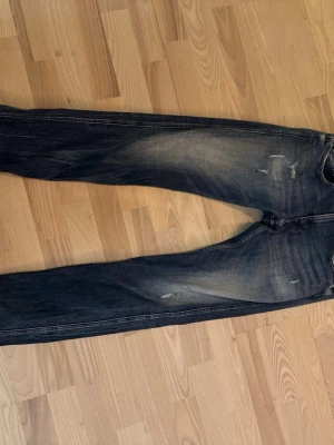 Mörkblå slim fit jeans med slitningar från Replay  - Snygga mörkblå slim fit jeans med diskreta slitningar och ljusare partier på låren och knäna. Klassisk femficksmodell med läderpatch bak i midjan. Perfekta för en trendig och avslappnad look.