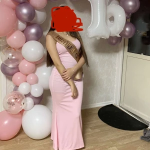 Ljusrosa ribbad långklänning med smala axelband - Säljer en ljusrosa långklänning med smala axelband och ribbad struktur. Klänningen har en enkel och stilren design som sitter snyggt längs kroppen. Perfekt för varma dagar eller som ett lagerplagg.