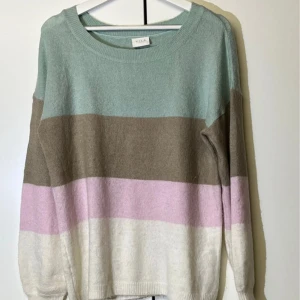 Randig pastelltröja från VILA - Supermysig stickad tröja från VILA med breda pastellfärgade ränder i mintgrönt, beige/brun, ljusrosa och vitt. Tröjan har rund halsringning och långa ärmar, perfekt för lager på lager under kyliga dagar.