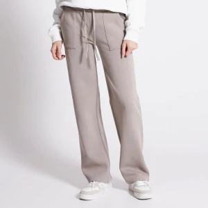 Beige mjukisbyxor med snörning - Snygga beige lågmidjade mjukisbyxor med raka, vida ben och bred resår i midjan. Byxorna har snörning framtill och fickor. Supersköna och snygg! Endast använda några få gånger, bra kvalitet!💞