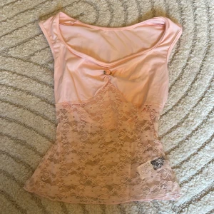 Ljusrosa spetslinne - Supersött ljusrosa linne med spetsdetaljer och liten rosett framtill. Genomskilnigt material där nere. Aldrig använt💕💕🌸