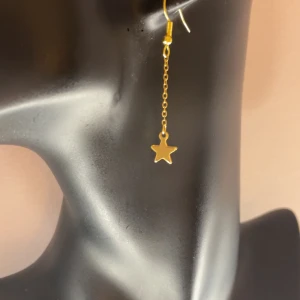 Långa stjärnörhängen - Ett par långa örhängen i guld. Pluttar ingår. Aldrig använda.