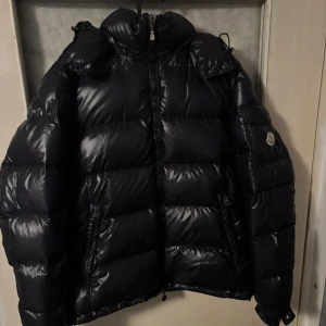 Svart Moncler pufferjacka med dragkedja - Säljer en svart pufferjacka från Moncler med glansig finish, hög krage och två dragkedjefickor framtill. Jackan har Moncler-logga på ärmen och klassisk quiltad design. Perfekt för kalla dagar och riktigt snygg streetstil. Om ni behöver mer bilder är det bara att skriva den är 100% äkta pris kan diskuteras vid snabb affär 