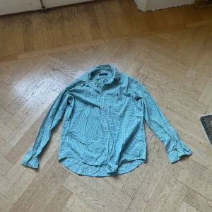 Rutig skjorta från Polo Ralph Lauren - Snygg rutig skjorta från Polo Ralph Lauren i grönt, blått och vitt. Klassisk krage, knäppning framtill och långärmad modell. Skjortan har broderad logga på bröstet och är tillverkad i mjuk bomull. Perfekt för en chill och stilren look.