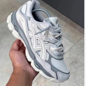 Gråvita sneakers från Asics - Säljer ett par snygga Asics sneakers i grått och vitt med mesh och syntetdetaljer. Skorna har en chunky sula och klassisk snörning, perfekt för dig som gillar sportig stil och vill ha bekväma skor till vardags. Stilsäkra och lätta att matcha med det mesta. De är knappt använda de är dubbel lacade där man får lådan och allt och priset kan diskuteras. Det passar folk med str 40 med och de är de jag har och 39 passar fint.