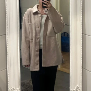  rosa kappa - Rosa kappa från Cubus med stora bröstfickor och knäppning framtill. Jackan har en rak och lite loose passform med långa ärmar och mjukt material som känns skönt mot huden. 