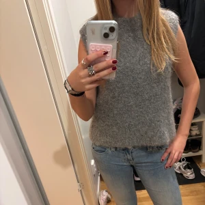 Grå stickad väst från H&M - Mysig grå stickad kortärmad tröja från H&M i ullblandning. Modellen är ärmlös med rak passform, perfekt att slänga över en skjorta eller t-shirt. Tröjan har en fluffig och mjuk känsla som ger en chill vibe till din outfit. Super mysig och inte stickig alls, köpt på Sellpy men säljer då den inte kommer till användning! 💕