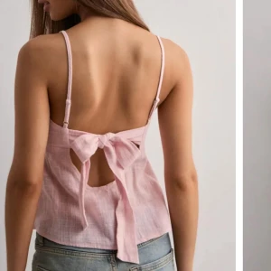 Ljusrosa linnetopp med rosett - Supersöt ljusrosa linnetopp med smala axelband och öppen rygg som knyts med en stor rosett. Toppen är ärmlös och har en luftig känsla, perfekt till jeans eller kjol. Materialet är lätt och ger en somrig vibe. Prislappen är kvar köpt för 249kr. Priset kan diskuteras 