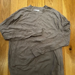 Brun långärmad tröja från Zara - En enkel och stilren brun långärmad tröja från Zara. Tröjan har rund halsringning och ribbade muddar vid ärmslut och nederkant. Perfekt för lager-på-lager och passar till det mesta i garderoben.