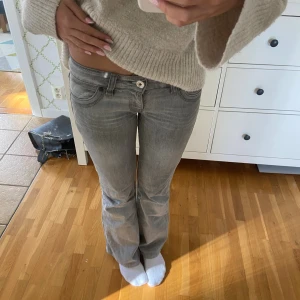 Grå bootcut jeans med låg midja - Super low waist snygga grå jeans med bootcut. Jätte fina med en liten design på fickorna. Perfekt passform som sitter tajt upptill och släpper vid benen. Tillverkade i mjukt denim-material. Köpte för 1500kr. Kolla in mina andra kläder säljer ett par mer low waist jeans!