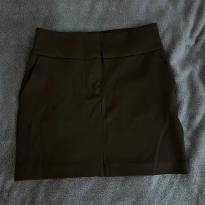 Svart kort kjol  - Svart kort kjol från Gina Tricot med fickor. Bara använd fåtal gånger så väldigt gott skick. Har dragkedja och två spännen att knäppa med. Storlek xs! 