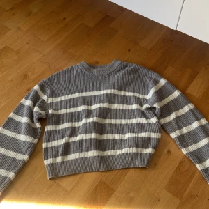 Gråvit randig stickad tröja - Supermysig stickad tröja i grått och vitt med breda horisontella ränder. Perfekt för lager-på-lager och chill dagar.
