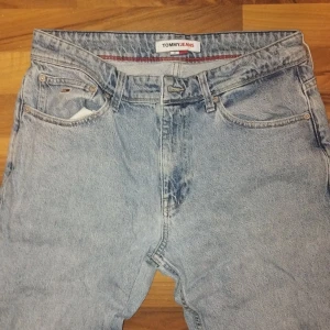 Tommy Jeans ljusblå raka jeans - Ljusblå jeans från Tommy Jeans med klassisk femficksdesign och raka ben. Snyggt broderad logga på bakfickan och stort flaggpatch bak i midjan. Jeansen har normal passform och är tillverkade i robust denim av bomull.