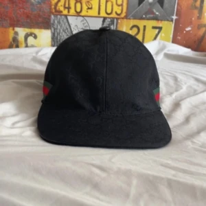 Svart keps från Gucci - Svart keps från Gucci med diskret GG-logomönster i tyget.