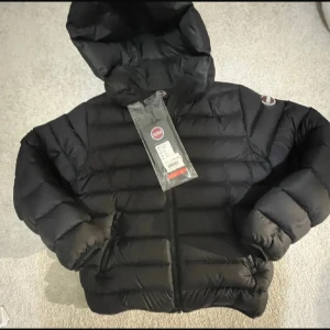 Svart Colmar pufferjacka med huva - Jätte fin svart colmar jacka i storlek 142cm 10år. Perfekt för hösten och vintern. Den är i perfekt skick utan några skador. Skicka gärna prisförslag, eller skriv om du har några funderingar 