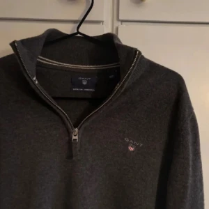 Mörkgrå halvziptröja från Gant - Säljer en snygg grå half zip från gant. Storlek M på tröja. Otroligt bra skick, inga tecken på användning. Hör av er vid frågor/priset