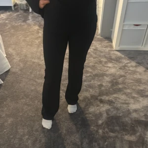 Svarta kostymbyxor med rak passform - Säljer ett par svarta kostymbyxor med rak passform och klassisk look. Byxorna har normal midja och stängs med knapp och dragkedja framtill. Perfekta för en clean och stilren outfit.