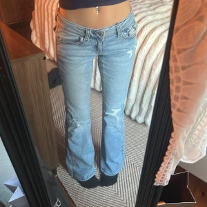 Ljusblå bootcut jeans. - Säljer ett par ljusblå bootcut jeans med låg midja och slitna detaljer på benen. Jeansen har klassiska fem fickor och snygga sömmar, tillverkade i denim. Perfekta för dig som gillar en avslappnad och trendig look. ‼️aldrig använda‼️ 